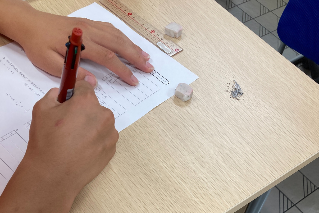 春日塾で個別演習に取り組む生徒の手元と学習プリント